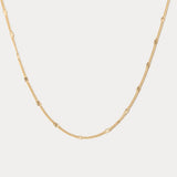 Gold chain necklace on a light gray background