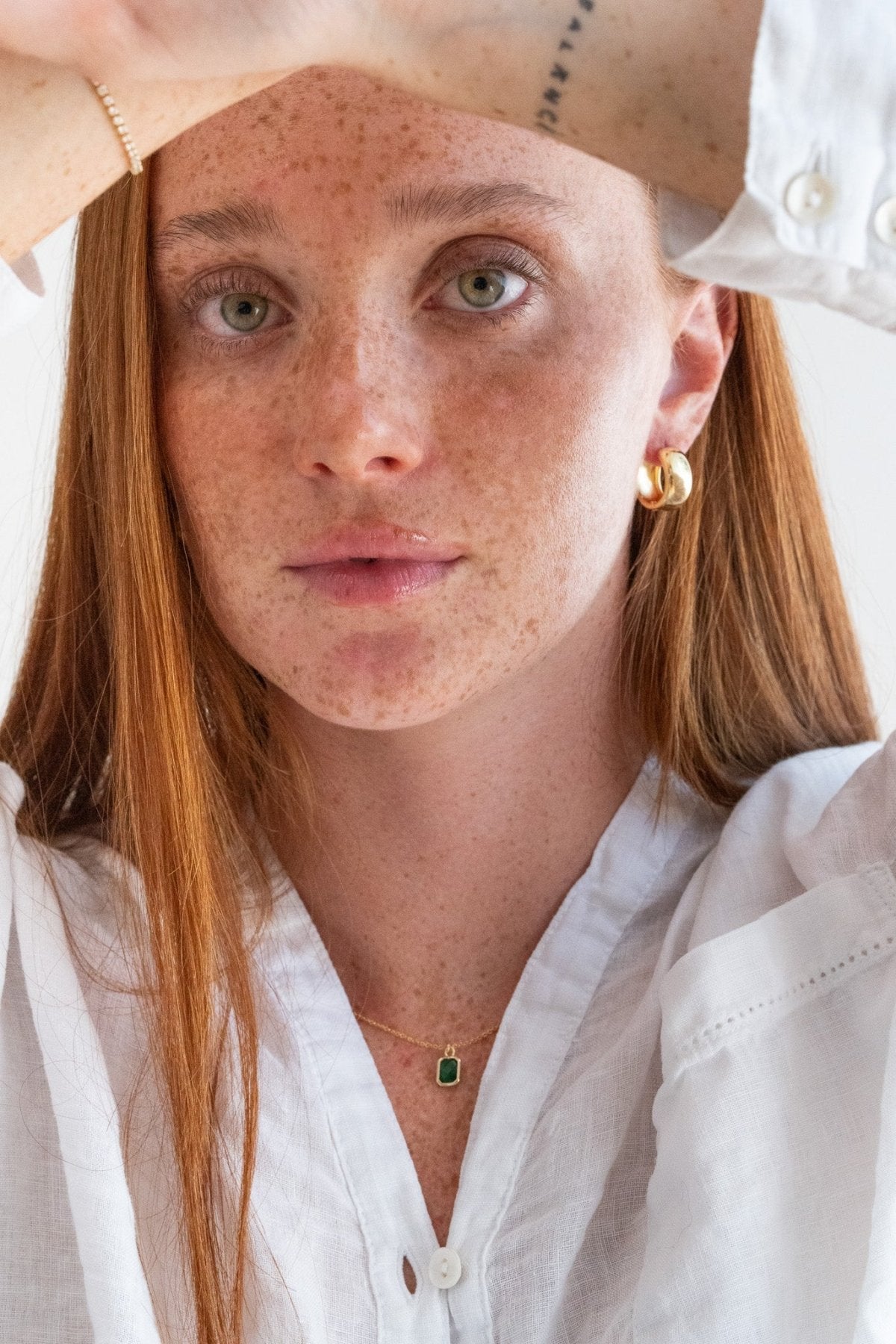 Person wearing a white shirt with a plain background