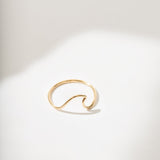 Gold ring with a wave design on a white background