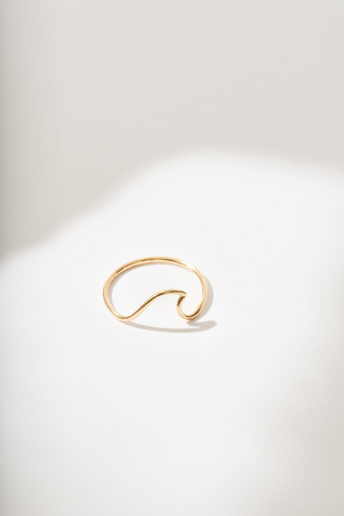 Gold ring with a wave design on a white background