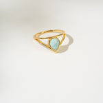 Gold ring with a triangular larimar gemstone on a white background