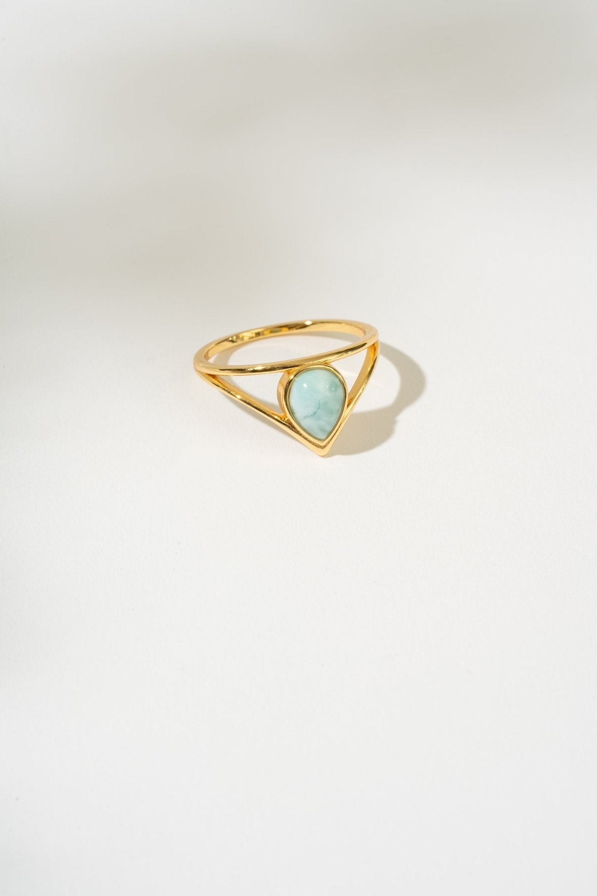Gold ring with a triangular larimar gemstone on a white background