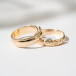 Two gold rings with intricate designs on a light background