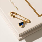 Close-up of a 'Something Blue' pin in gold, featuring a subtle blue gemstone set in a sleek, timeless design. This elegant accessory adds a touch of tradition and charm to the bride’s ensemble, offering a meaningful and stylish detail on her wedding day.