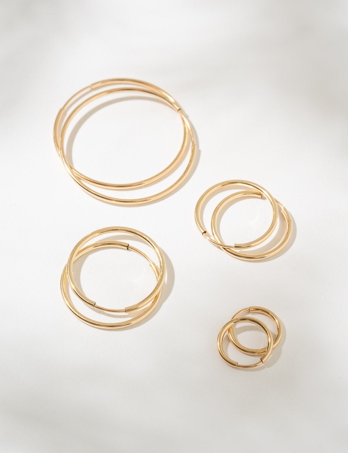 Set of gold hoop earrings on a light gray background