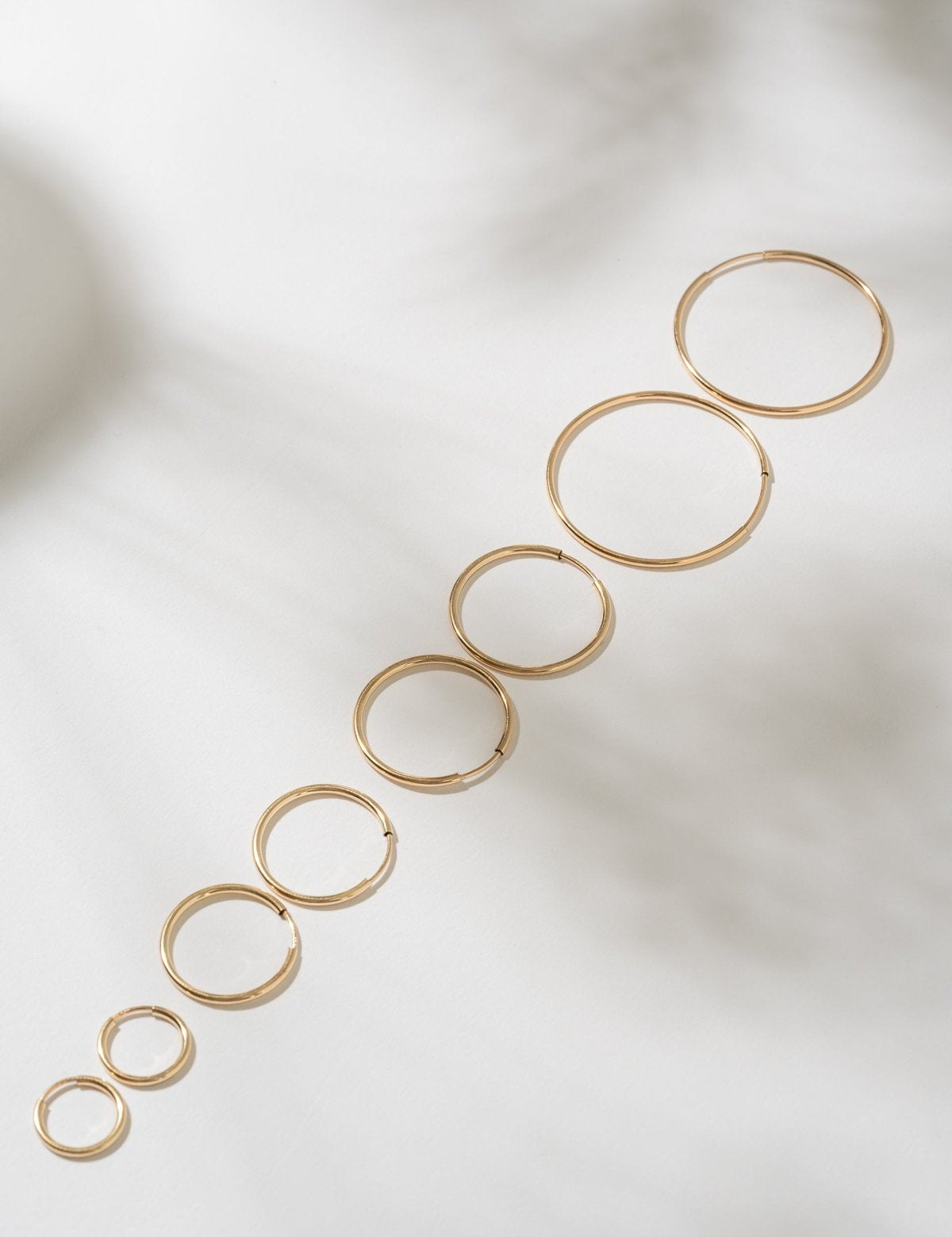 Set of gold hoop earrings on a light background