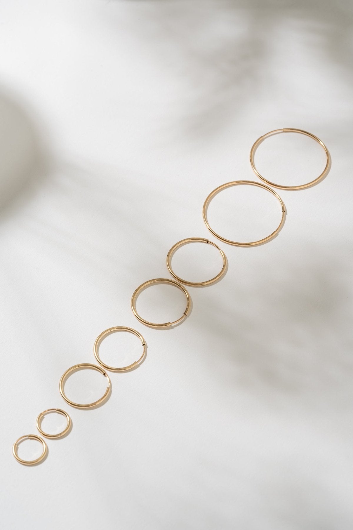 Set of gold hoop earrings on a light background