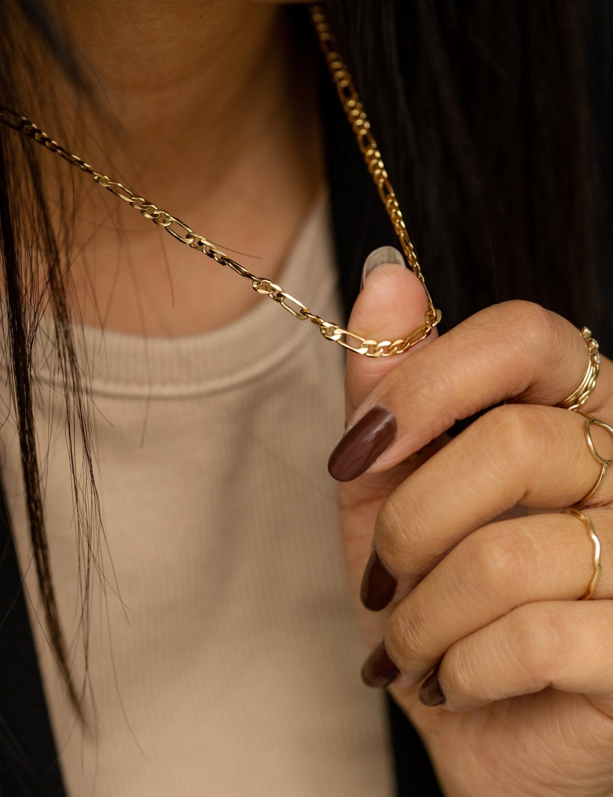 Close-up of the gold-plated Figaro chain highlighting its alternating link pattern.