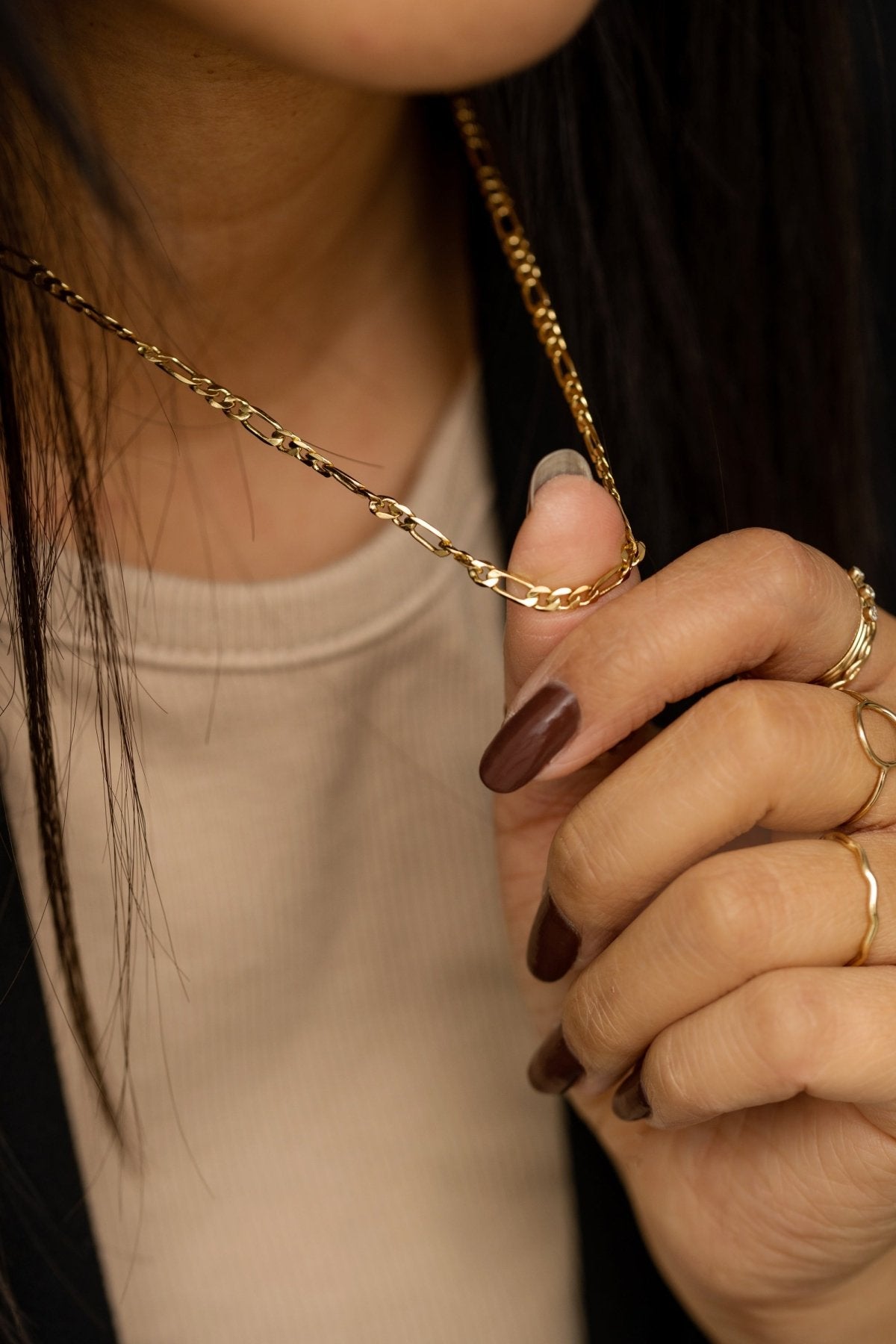 Close-up of the gold-plated Figaro chain highlighting its alternating link pattern.